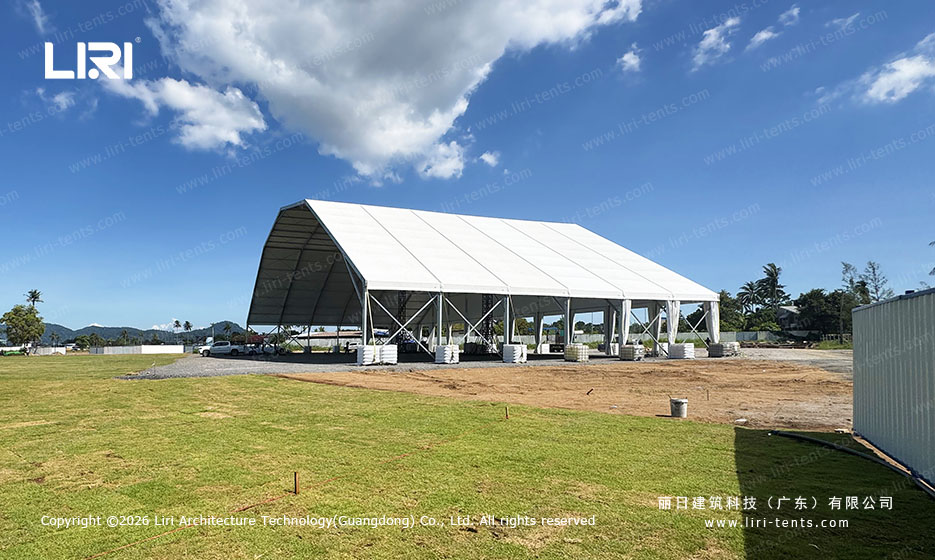 50x30m event tent exterior with trucks staged inside, white side curtains, tropical palm tree setting