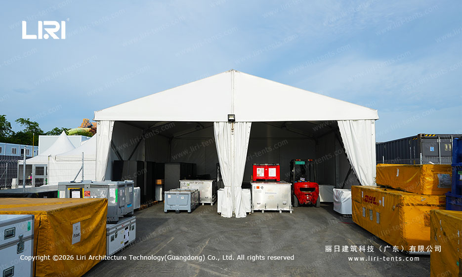 A-frame support tent with drawn curtains beside race-day generator stacks