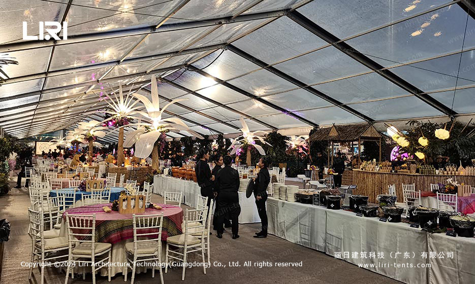 Banquet hall guests networking under transparent tent roof