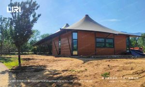 Glass wall tent exterior with wooden cladding and peak roof