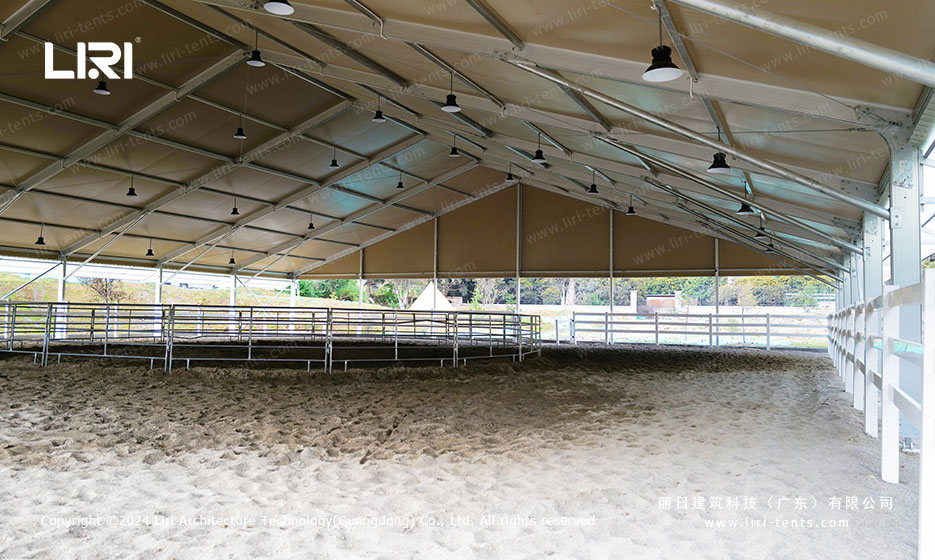 Horse riding arena interior showing sand footing and steel perimeter rail