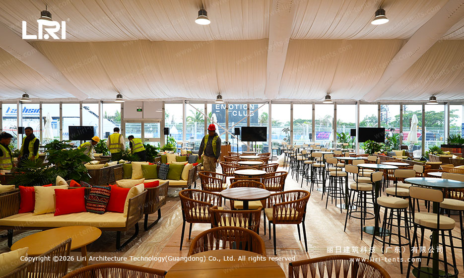 Hospitality lounge with glass walls, sofas and high tables inside the Sanya event tent