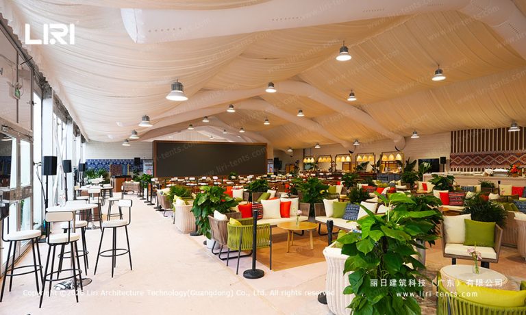 Long hospitality hall with sofas, plants and large LED screen inside the Sanya event tent