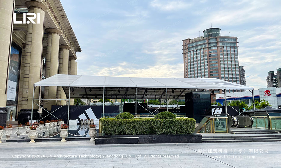 Temporary party tent set up in a city square with adjacent glass towers