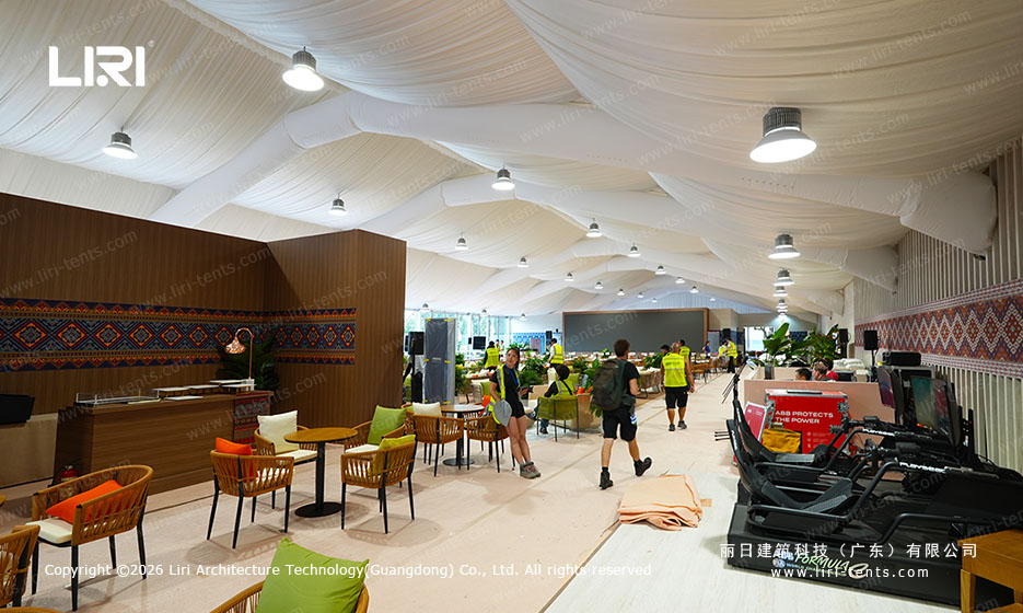 VIP lounge with fabric draped ceiling and rattan furniture inside the hospitality tent