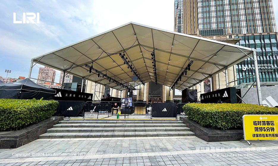 White PVC event tent facade with entrance steps and floral planters outside a Shanghai shopping mall