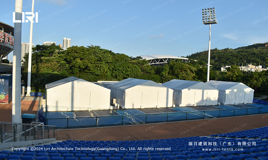 white warehouse tent set up beside tennis court for back-of-house storage