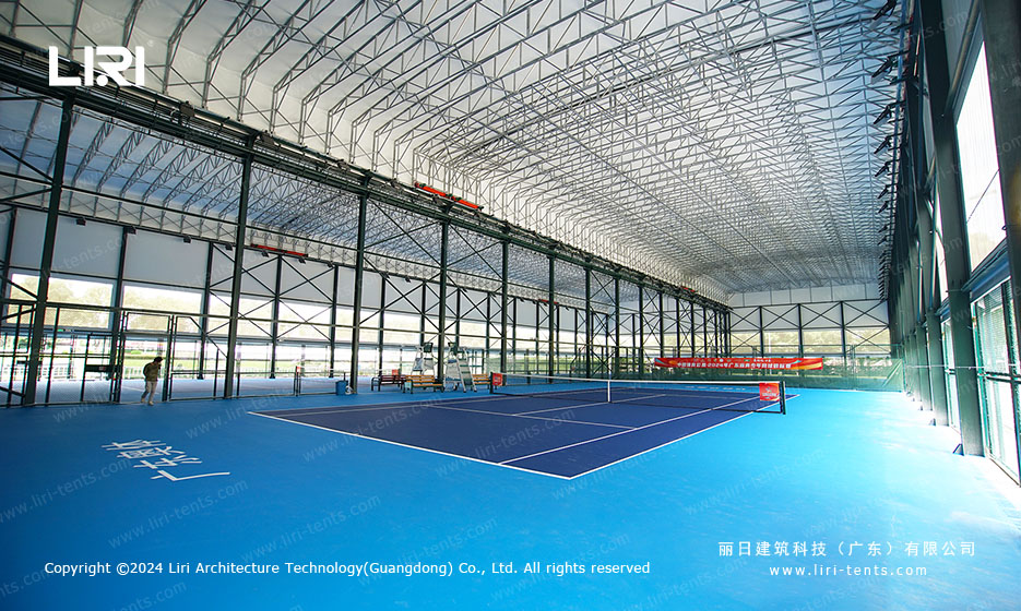 Wide interior view of multiple tennis courts under one roof