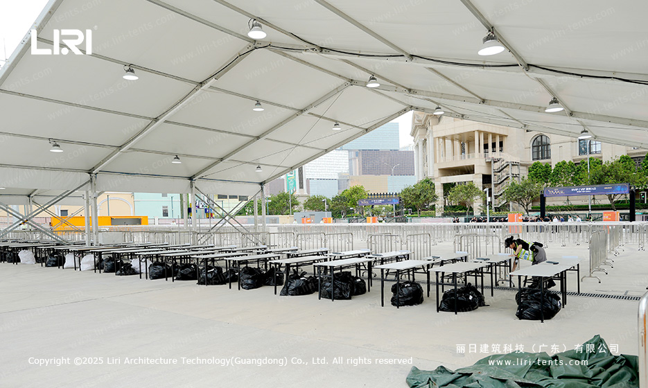 Banquet table rows inside an award ceremony party tent with white PVC ceiling and pendant lights overhead