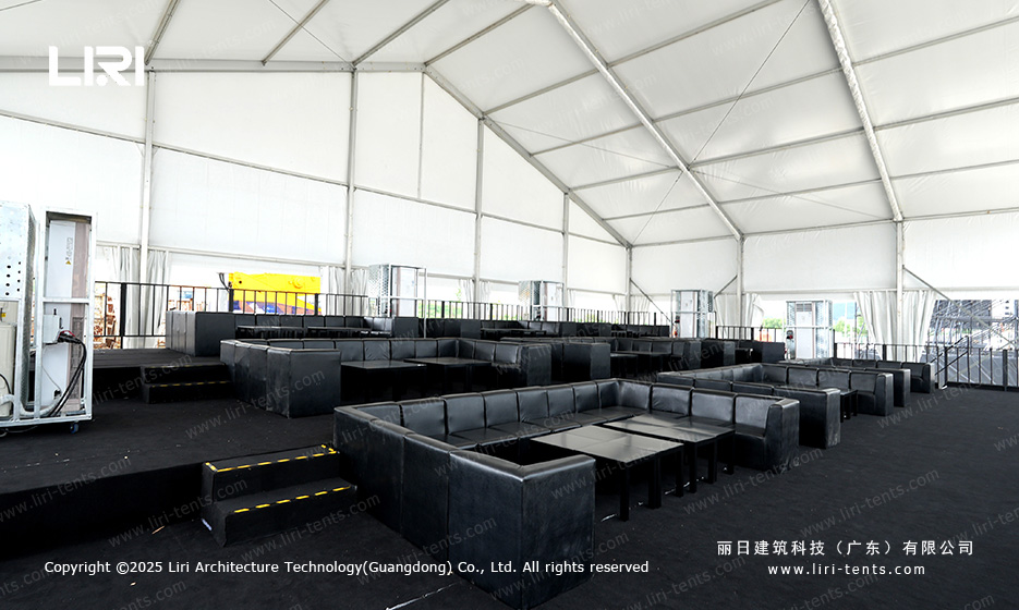 VIP box seating with black leather sofas arranged in square layouts inside a clear span award ceremony party tent