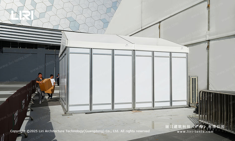 Modular white entry pavilion with glass walls attached to the gable end of an opening ceremony party tent on a Shenzhen plaza