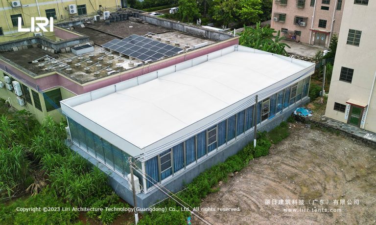Aerial view of a flat-roof modular meeting room tent installed between two concrete factory buildings