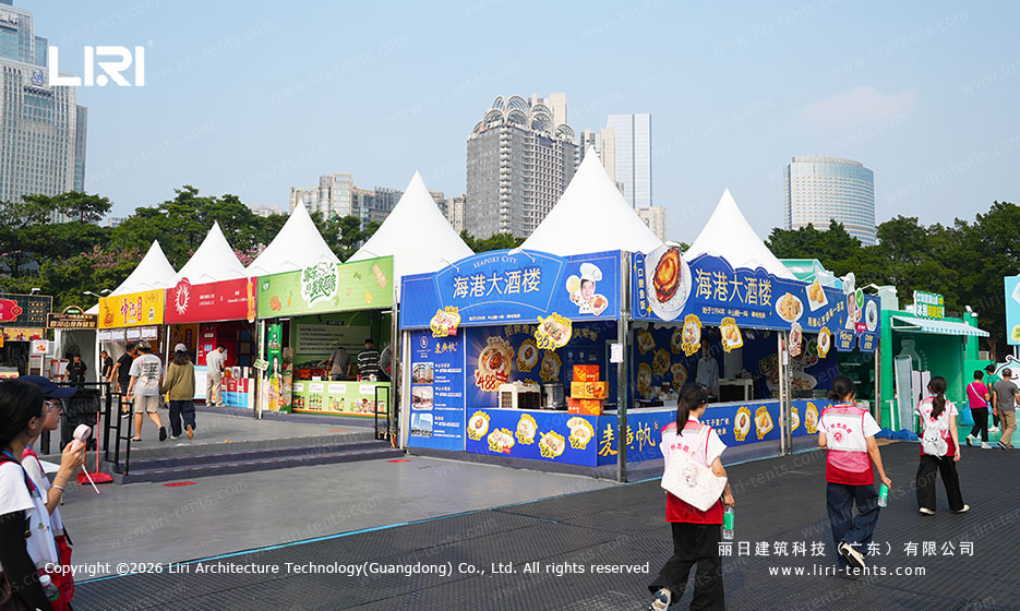 Row of white high peak food stalls with visitors on an outdoor route