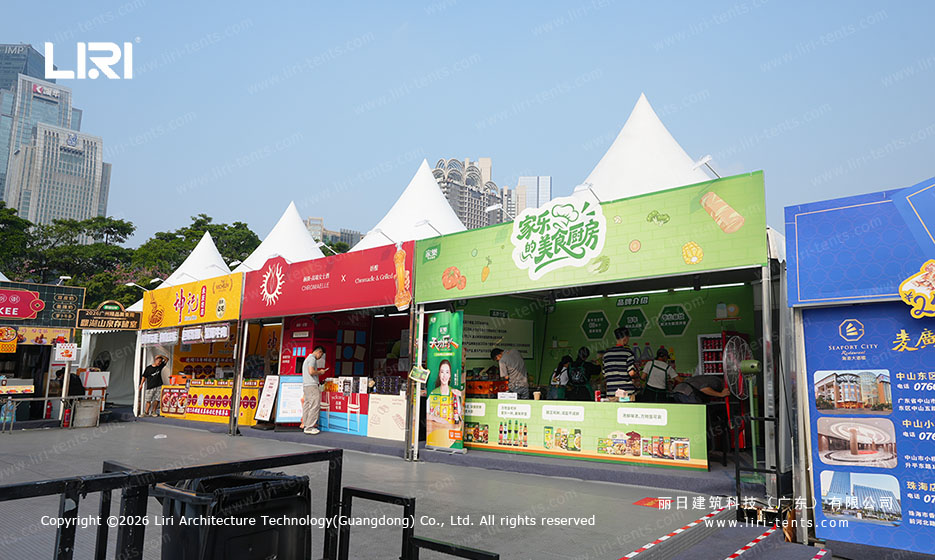 Food vendor counters beneath a repeating high peak tent roofline